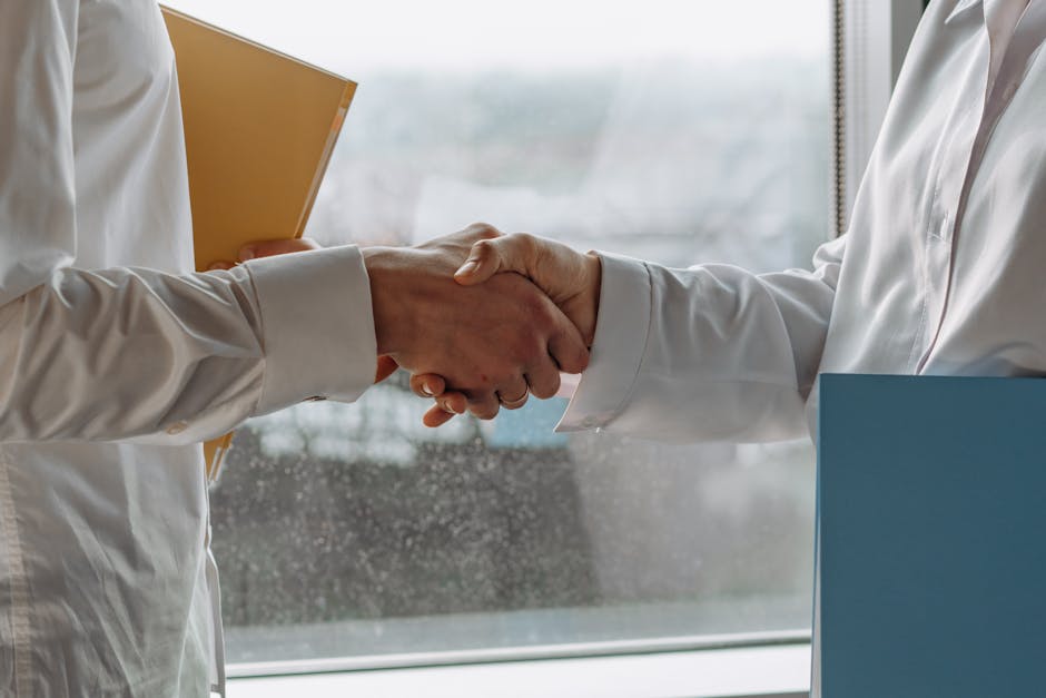 Two business professionals shaking hands indoors, symbolizing agreement.