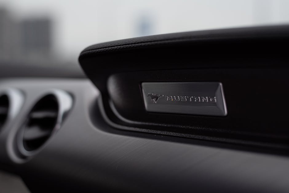 Interior detail of Ford Mustang featuring chrome logo, showcasing luxury automotive design.