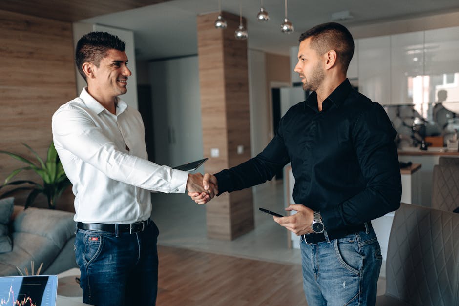 Two business professionals shaking hands in a modern office environment, symbolizing partnership.